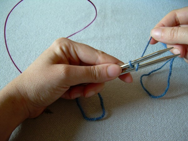 Fai passare il filo attorno al ferri inferiore da dietro in avanti e tra i due ferri