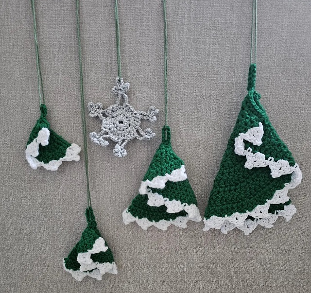 Alberelli di Natale verdi con bordo a pizzo biancor, realizzati a uncinetto, piegando un semicerchio su sé stesso. Modello di Susanna Biaye.