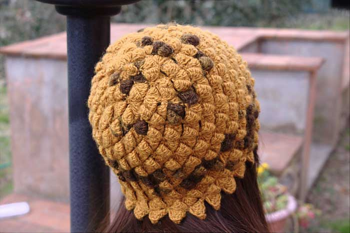 Una modella, di spalle, indossa un cappellino a uncinetto senape e testa di modo, realizzato con un punto fantasia. Foto di Borgo de' Pazzi, modello di Veruska Happysloth.